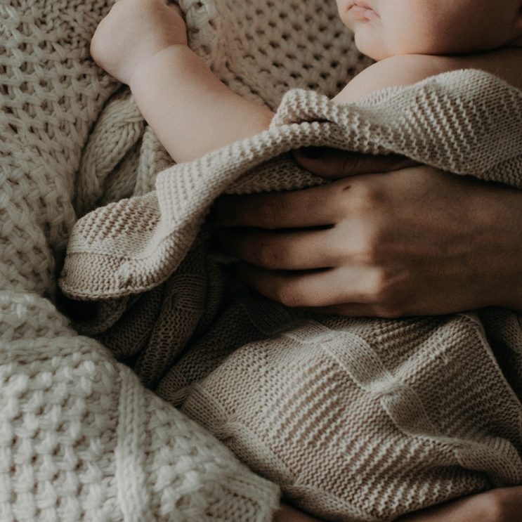 Mutter hält Baby im Arm im Wochenbett